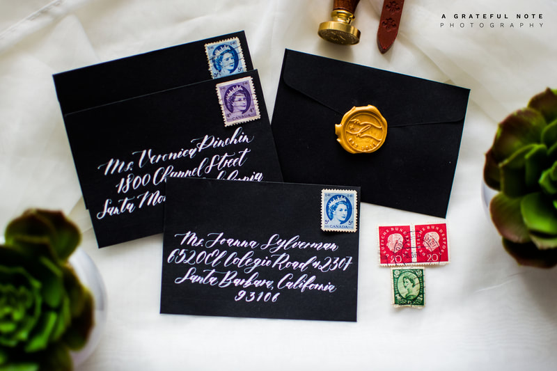 Custom White Calligraphy Addressing on Black Envelopes with Gold Wax Seal and Vintage Stamps Alternate Flatlay.